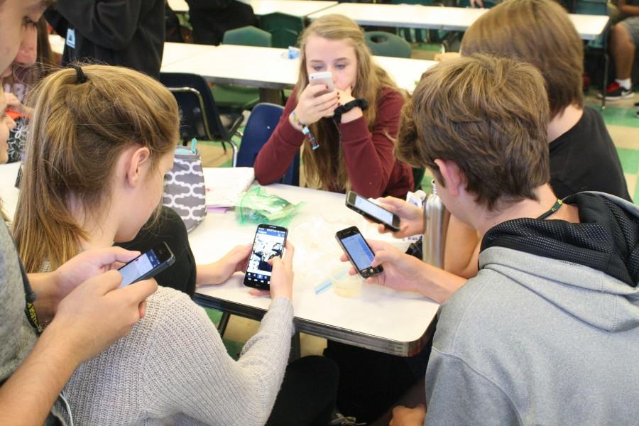 A group of students use their favorite apps during lunch.