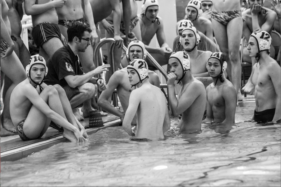 The boys water polo team discusses the match with their coach during a time out.