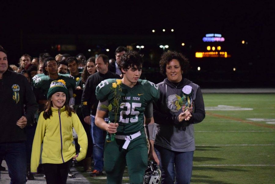 One of the captains for the Football team, Jacob Clohisy, walks with his parents and sister as he is honored on Senior night
