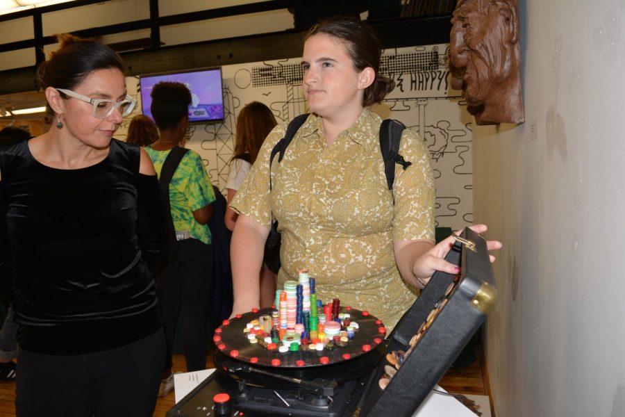 Rose Olejniczak, Div. 876, showing her artwork, “Tower of Buttons,” to Joanna Maciaszkiewicz Perez, Director of Alumni Relations for the Alumni Association, at the student-alumni art show in Gallery 2501 on Sept. 14.