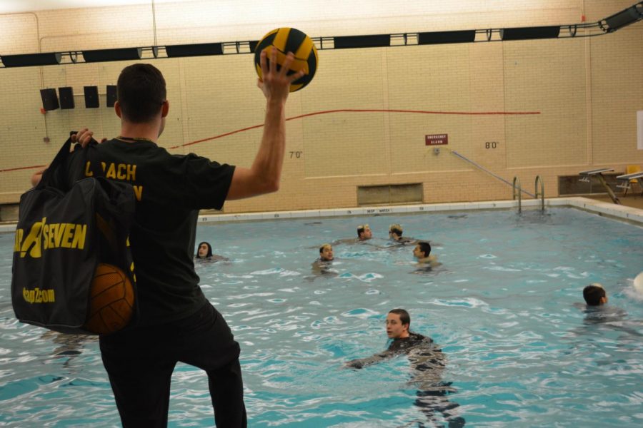 Three year head coach of the water polo team Mathew OHagan giving players balls in practice.
