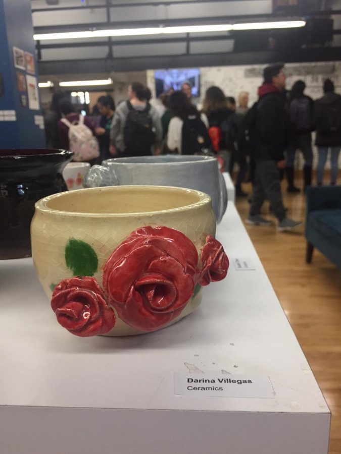 Rosed ceramic mug in front of crowd of students on the opening reception day of the Spring Art Show on March 1.
