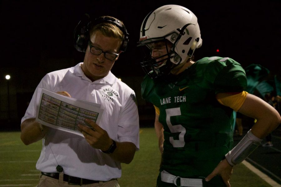 Assistant Varsity football coach Pat Czerwiec goes over plays with senior quarterback Luke Calkins during the team’s game against Simeon on Sept. 15. (Photo courtesy of Stefan Rebic)