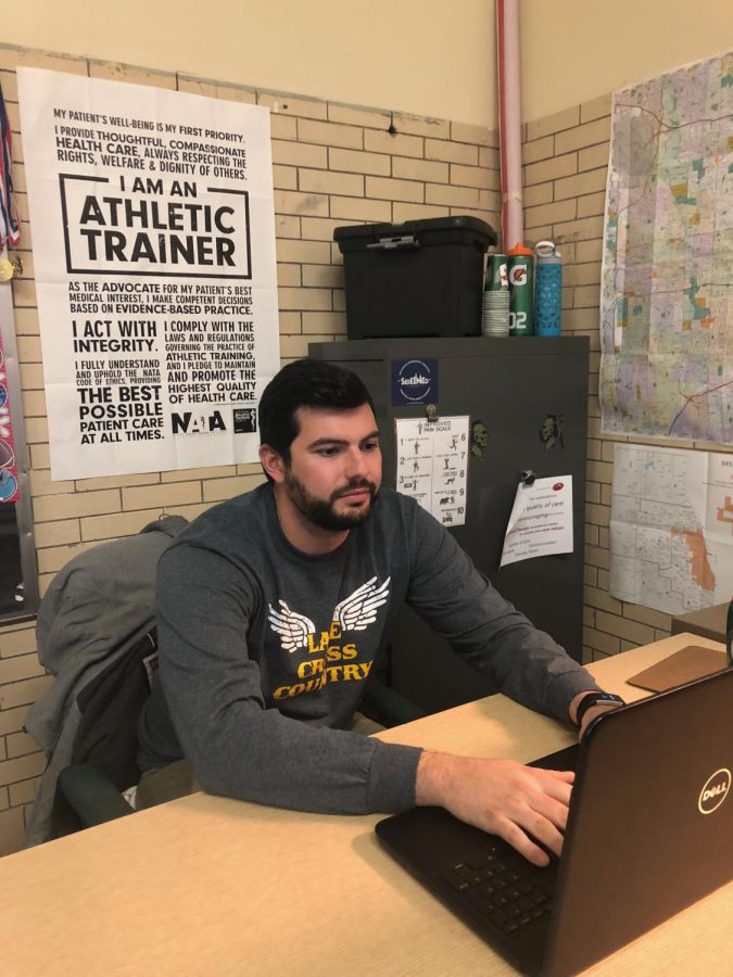 Athletic Trainer Aristides Adrahtas, better known as Ari, working on his laptop to log in information about current injuries. 
