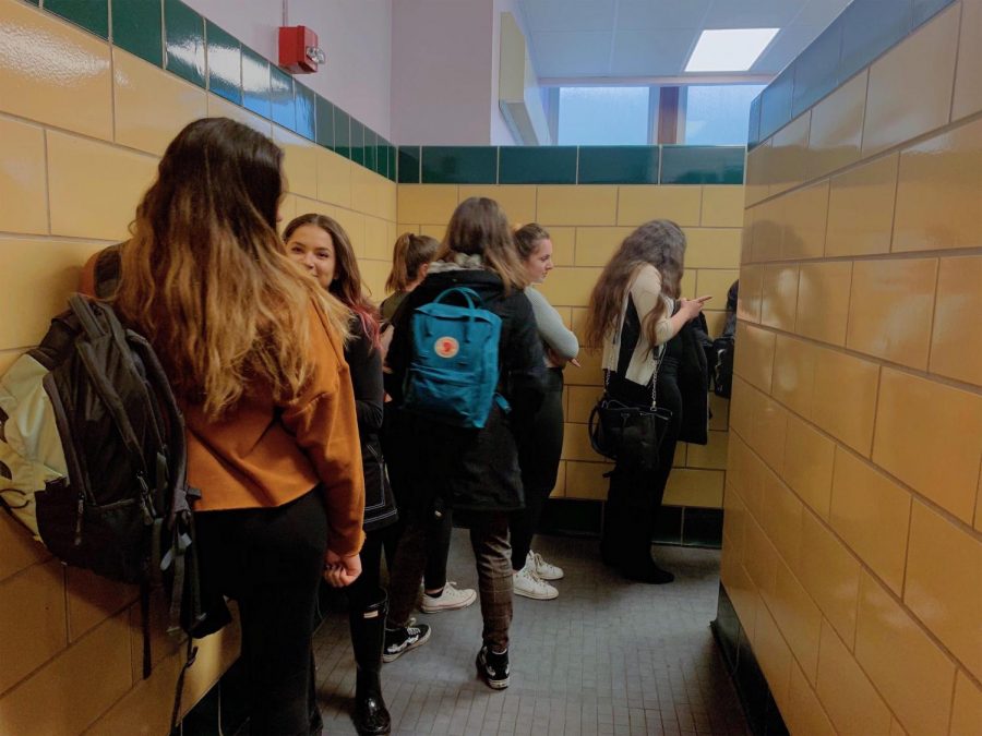 Students chat with friends to pass the time as they wait in a typical line for the girls’ bathroom.
