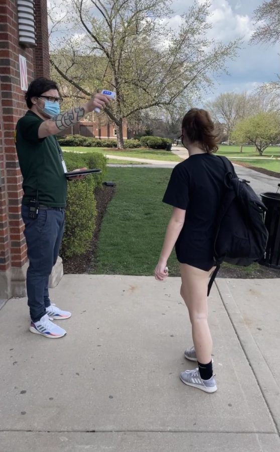 A student passes a temperature check before being allowed in the building for volleyball in April.