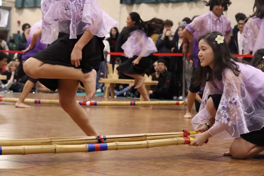 Senior Cholpon Nurgazieva of Filipino Club moves two bamboo poles together as dancers step over and in between the poles in a traditional Philippine folk dance known as Tinikling.